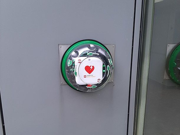 Öffentlicher AED links an der Wand neben der Nebeneingangstür