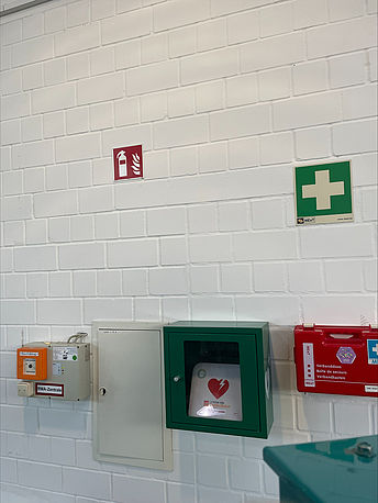 Durch den Haupteingang geradeaus, AED im Wandkasten an der Wand gegenüber Durch den Haupteingang geradeaus, AED im Wandkasten an der Wand gegenüber